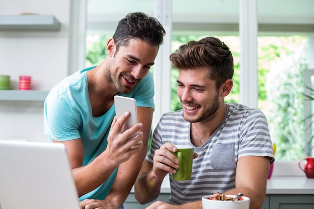 Lächelnder Mann, der dem Freund Telefon zeigt