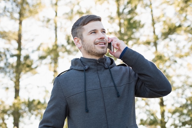 Lächelnder Mann, der draußen Handy verwendet