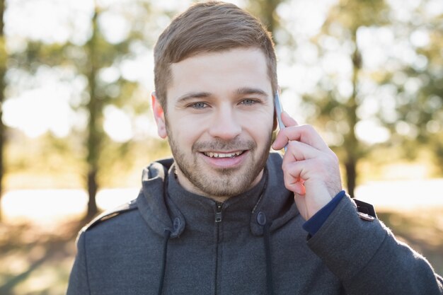 Lächelnder Mann, der Handy im Wald verwendet