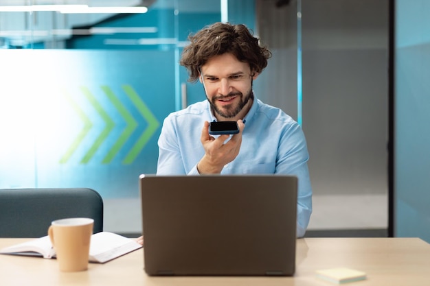 Lächelnder Mann, der im Büro arbeitet und telefoniert