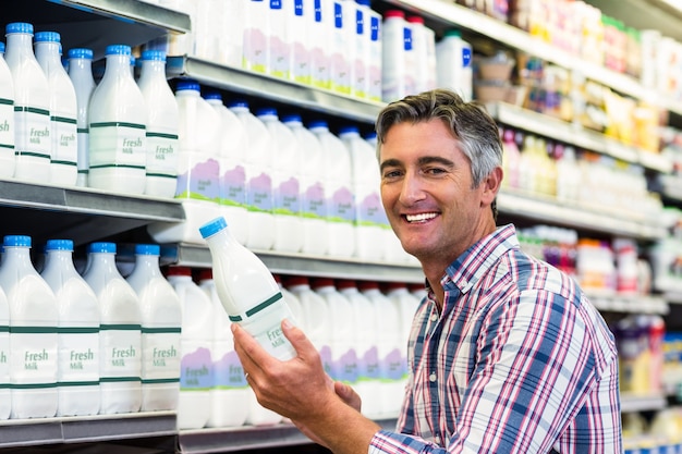 Lächelnder Mann, der Milchflasche hält