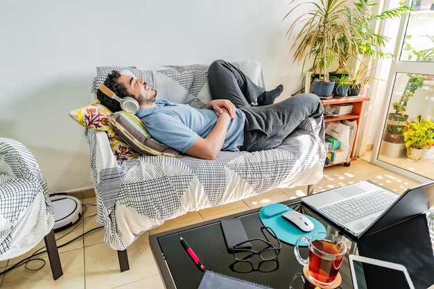 Lächelnder Mann, der Musik hört, macht Pause im Heimbüro