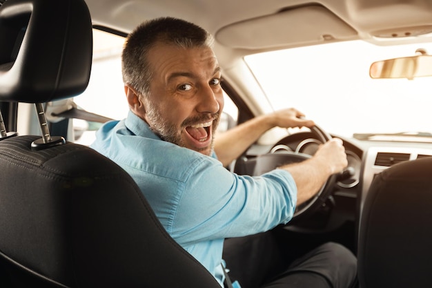 Lächelnder Mann, der neues Auto in der Stadt fährt