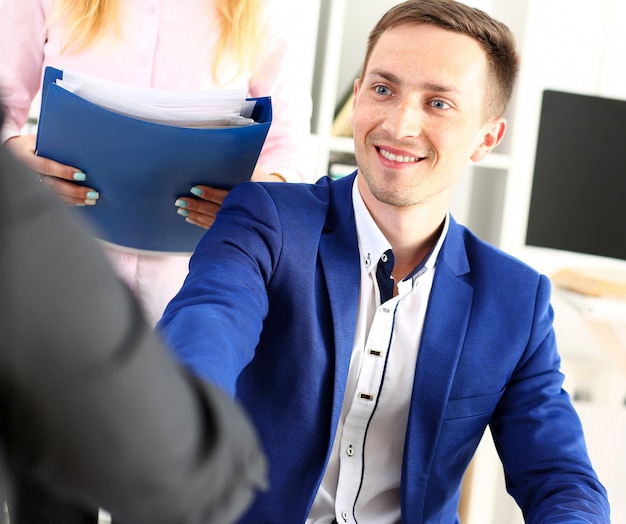 Foto lächelnder mann im anzug schüttelt hände als hallo im büro