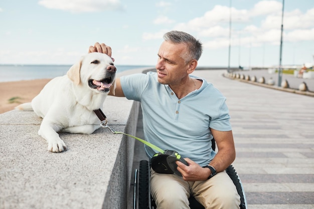 Lächelnder Mann im Rollstuhl gehenden Hund