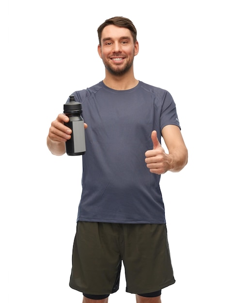 lächelnder Mann mit Sportflasche zeigt Daumen nach oben