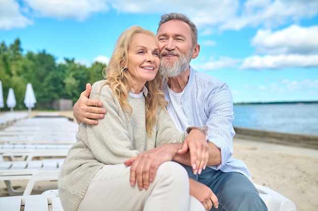 Lächelnder Mann und Frau sitzen am Meeresstrand