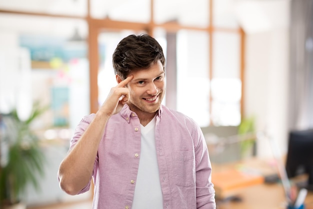 lächelnder Mann zeigt mit dem Finger auf seinen Kopf im Büro