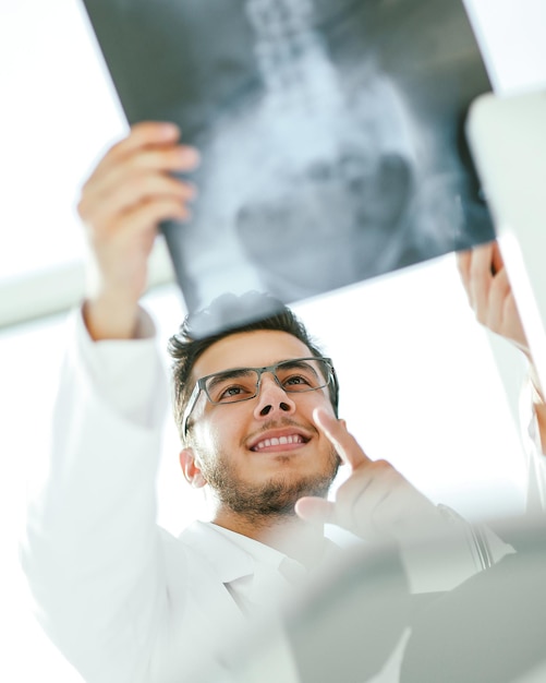Lächelnder orthopädischer Arzt betrachtet das Röntgenbild des Patienten .photo mit Kopienraum