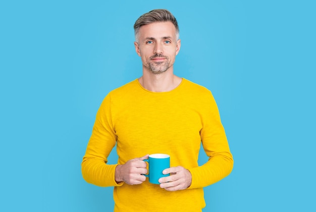 Lächelnder reifer Mann bei der Kaffeepause im Studio reifer Mann bei der Kaffeepause im Hintergrund