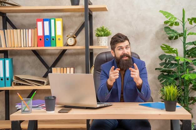 Lächelnder reifer Unternehmer, der am Computer im Büro arbeitet