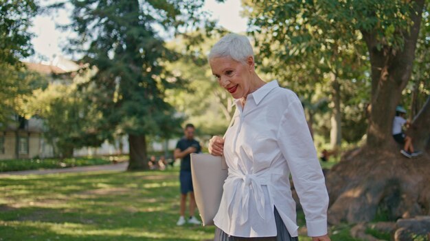 Lächelnder Rentner genießt einen Spaziergang im Sommerpark, sorgloser Senior bewundert die Natur