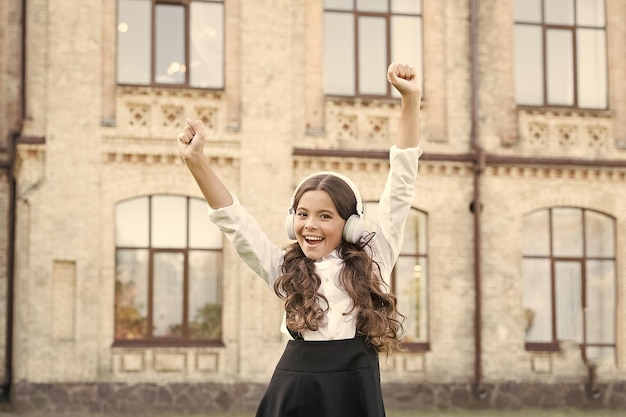 Lächelnder Schüler Echter Erfolg Fröhliches Kind im Freien Fröhliches Schulmädchen Schulmädchen entspannt Glückliches Kindheitskonzept Internationaler Kindertag Fröhliches Lied Freizeit und Ruhe Wunderschöne Frisur