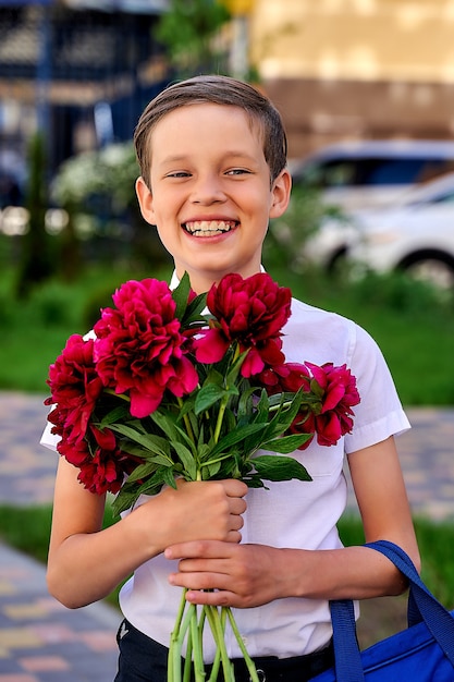 Foto lächelnder schuljunge mit blumenstrauß