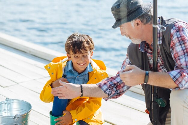 Lächelnder Schuljunge, während er mit Großvater über das Fischen diskutiert