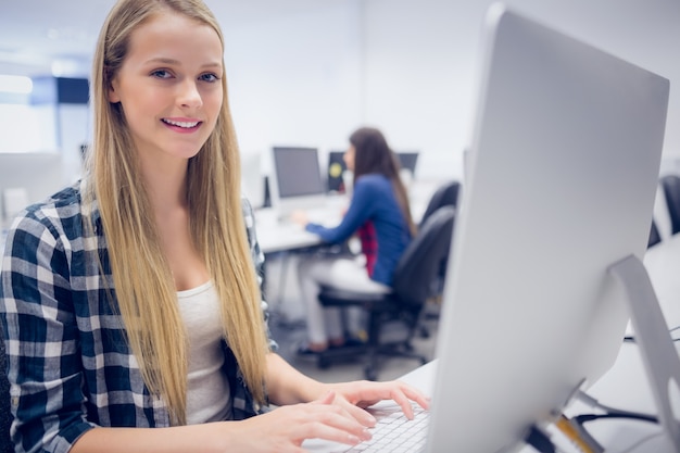 Foto lächelnder student, der an computer an der universität arbeitet