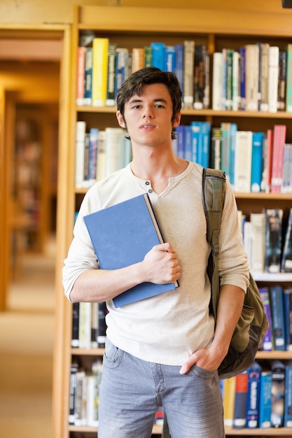 Lächelnder Student, der mit einem Buch aufwirft