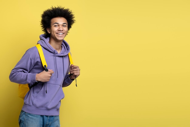 Lächelnder Student mit Rucksack isoliert auf gelbem Hintergrund, Kopierraum. Ausbildung