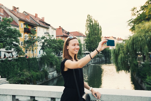 Lächelnder Tourist auf dem Hintergrund des Stadtbildes von Ljubljana mit Fluss und Häusern bei Sonnenuntergang