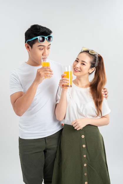 Lächelnder trinkender Saft des glücklichen Paars auf weißem Hintergrund