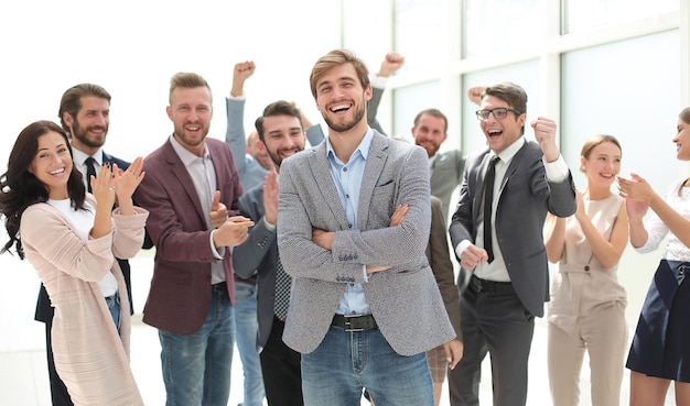 Lächelnder Unternehmer auf dem Hintergrund eines jubelnden Geschäftsteams
