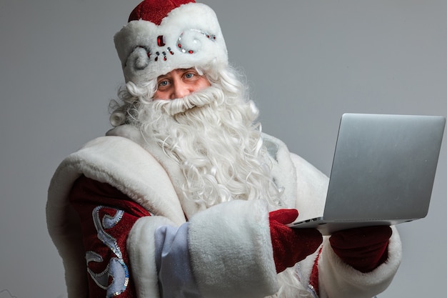 Lächelnder Väterchen Frost mit Laptop in den Händen.