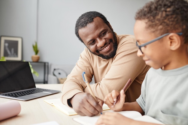 Foto lächelnder vater, der dem sohn beim studieren hilft