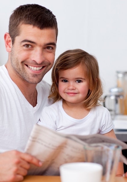 Lächelnder Vater, der eine Zeitung mit seiner Tochter liest