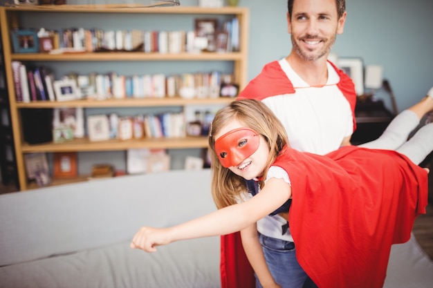 Lächelnder Vater, der tragendes Superheldkostüm der Tochter hält