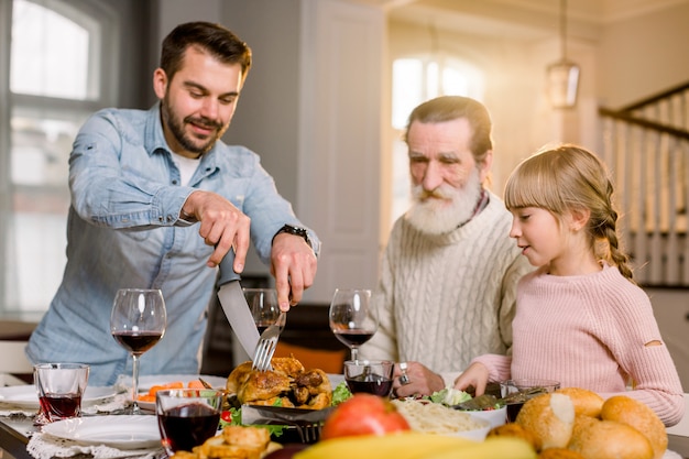 Lächelnder Vater, der Truthahnscheiben für Familienessen schneidet