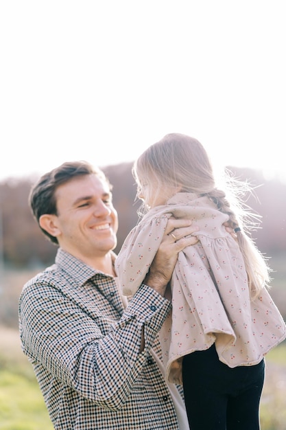 Lächelnder Vater hält kleines Mädchen in seinen Armen, während er auf dem Rasen steht