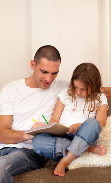 Lächelnder Vater und seine Tochter, die auf einem Sofa sitzen