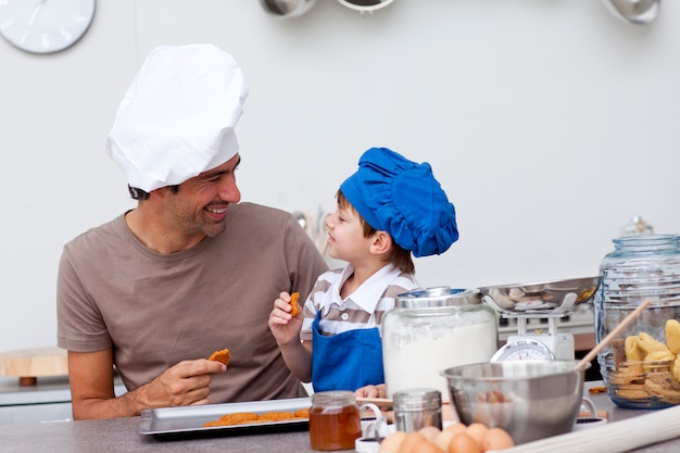 Lächelnder Vater und Sohn, die selbst gemachte Plätzchen essen