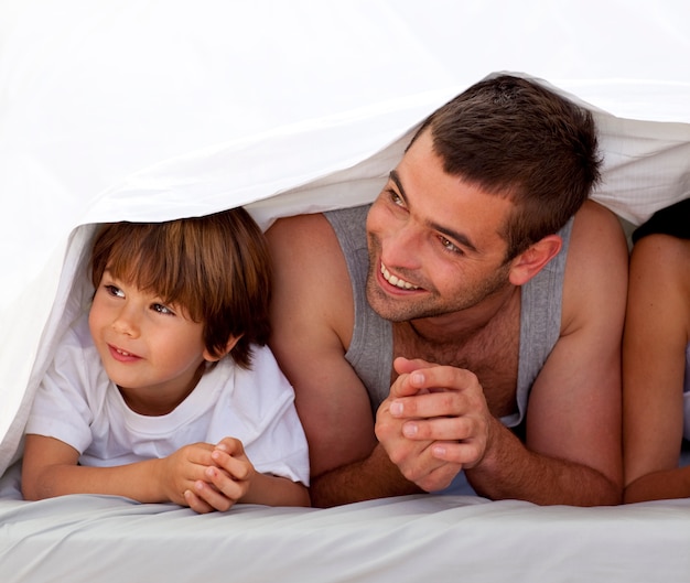 Lächelnder Vater und Sohn unter den Bettlaken