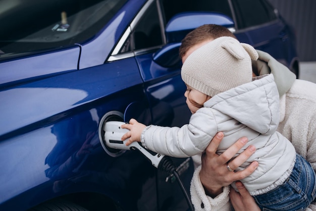 Lächelnder Vater und Tochter, die zu Hause Elektroautos aufladen