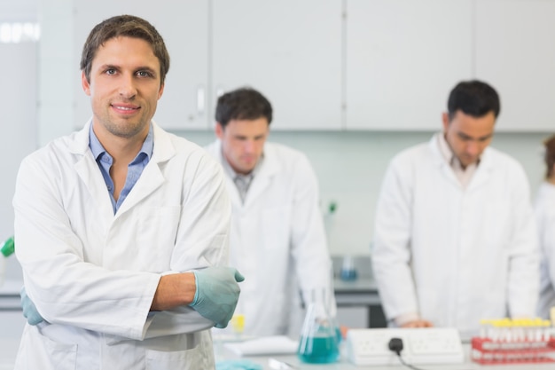 Lächelnder Wissenschaftler mit Kollegen bei der Arbeit im Labor