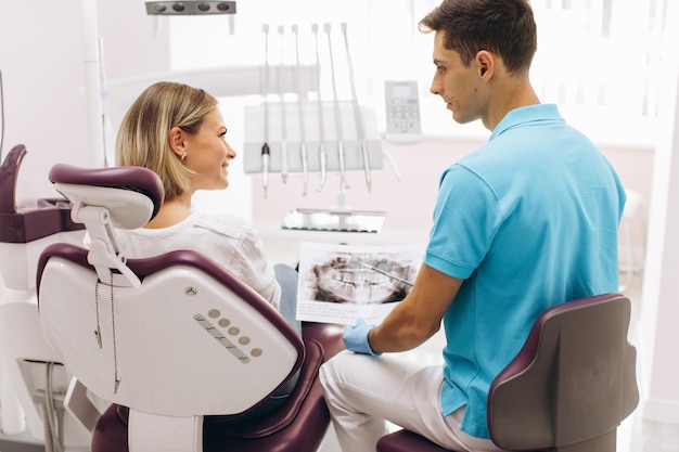Lächelnder Zahnarzt, der Patientin in der Zahnklinik Röntgen zeigt