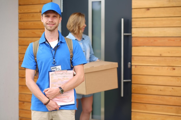 Lächelnder Zusteller in blauer Uniform liefert Paketbox an Empfänger Kurierdienstkonzept Smil