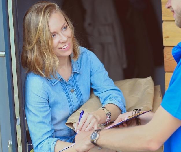 Foto lächelnder zusteller in blauer uniform liefert paketbox an empfänger kurierdienstkonzept smil