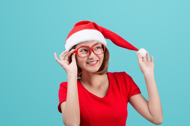 Lächelndes asiatisches Frauenporträt mit Weihnachtssankt-Hut lokalisiert auf blauem Hintergrund.