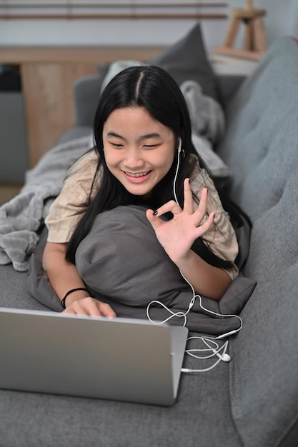 Lächelndes asiatisches Mädchen, das zu Hause einen Videoanruf auf dem Computer-Laptop hat.