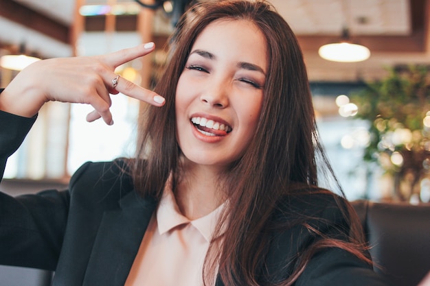 Lächelndes asiatisches Mädchen des schönen reizend Brunette, das selfie auf Frontkamera am Café nimmt