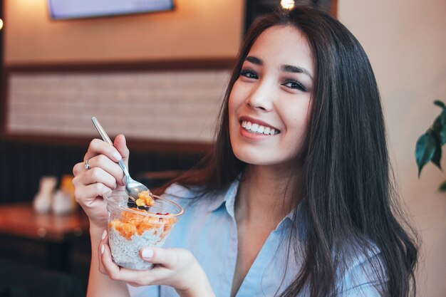 Lächelndes asiatisches Mädchen des schönen reizend Brunette frühstückt mit Chia-Pudding am Café