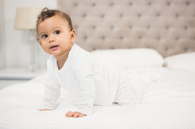 Lächelndes Baby auf dem Bett, das herum schaut