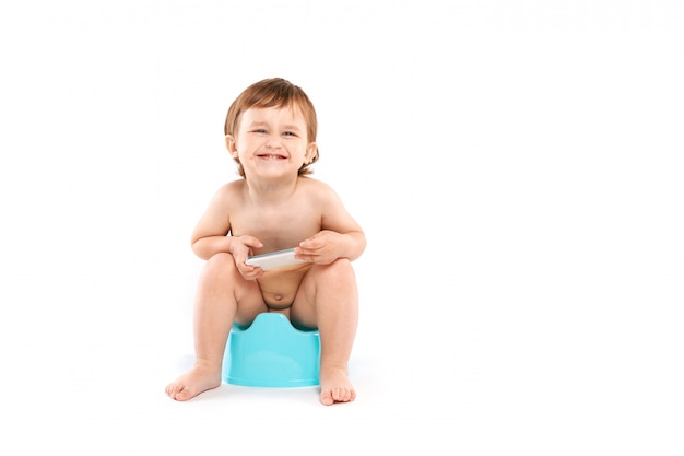 Lächelndes Baby mit einem Telefon auf dem Töpfchen