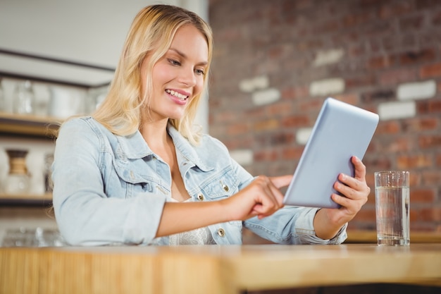 Lächelndes blondes Berühren auf Tablet-Computer