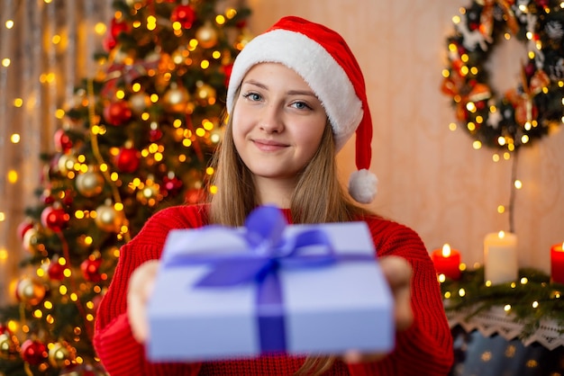 Lächelndes blondes Mädchen, das glücklich ist, Freunde und Verwandte mit einem kostbaren Geschenk zu überraschen