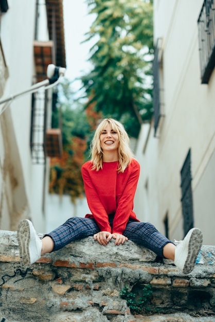 Lächelndes blondes Mädchen mit rotem Hemd das Leben draußen genießend.