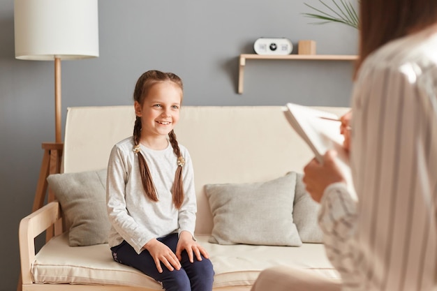 Lächelndes charmantes Mädchen im Büro des Psychologen im Gespräch mit Arzt Schulmädchen Patient Psychotherapie Beratung Kinder Trauma Behandlung professionelle Hilfe