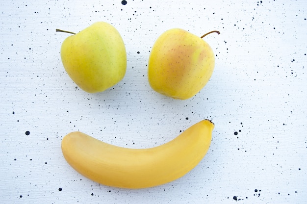 lächelndes Emoji aus Früchten auf weißem Hintergrund mit schwarzen Punkten flach Draufsicht